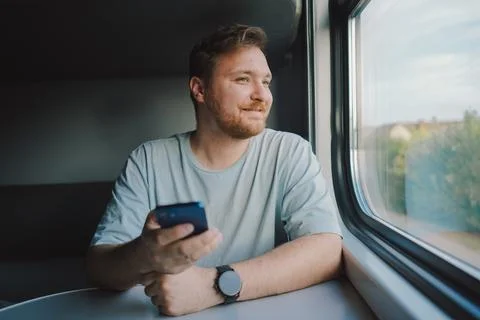 A man using a smartphone while traveling by Railway train Stock Photos