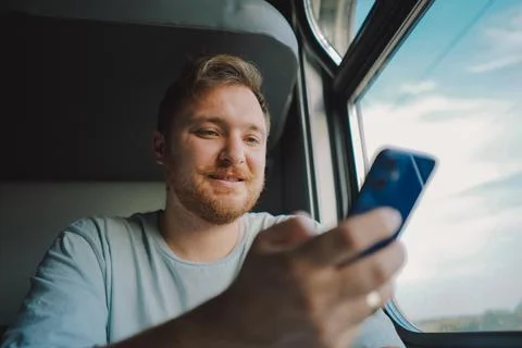 A man using a smartphone while traveling by Railway train Stock Photos