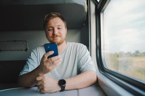 A man using a smartphone while traveling by Railway train Stock Photos