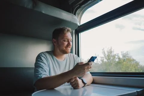 A man using a smartphone while traveling by Railway train Stock Photos