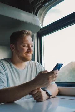 A man using a smartphone while traveling by Railway train Stock Photos
