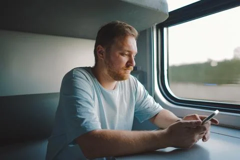 A man using a smartphone while traveling by Railway train Stock Photos