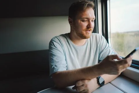 A man using a smartphone while traveling by Railway train Stock Photos