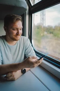 A man using a smartphone while traveling by Railway train Stock Photos
