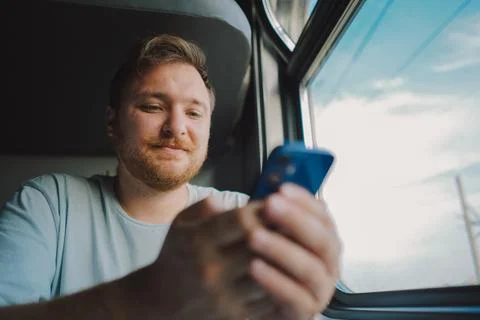 A man using a smartphone while traveling by Railway train Foto stock