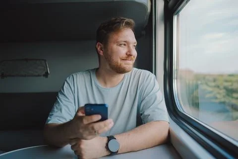 A man using a smartphone while traveling by Railway train 스톡 사진