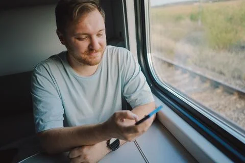 A man using a smartphone while traveling by Railway train Stock Photos