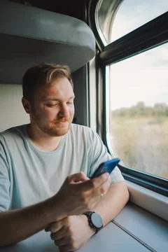 A man using a smartphone while traveling by Railway train Stock Photos