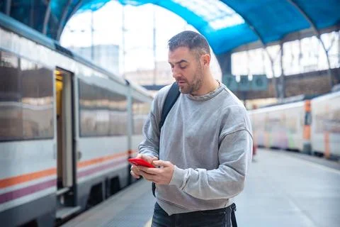 Man Using Smartphone While Waiting at Train Station Stock-Fotos