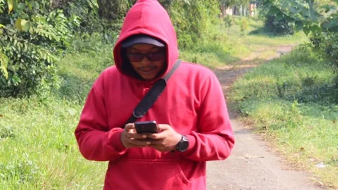 Man using a smartphone while walking along a rural path Stock Footage 337275469