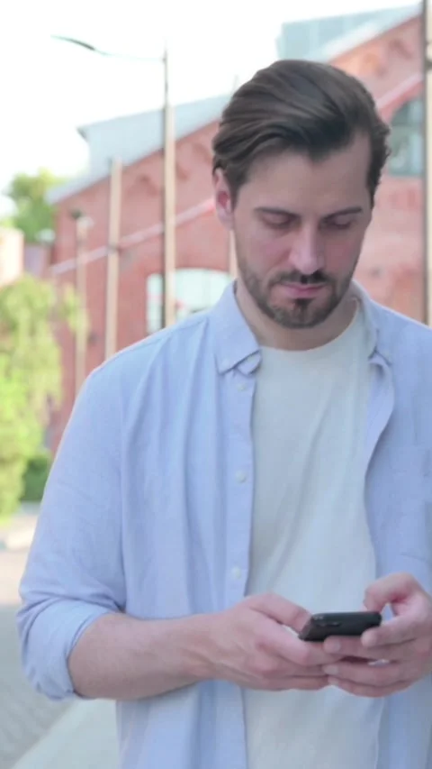Man using Smartphone while Walking in Street, Slow Motion , Vertical Video Stock Footage 339666423