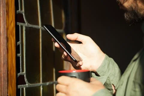 Man using smartphone from a window Stock Photos