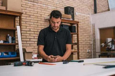 Man using a smartphone in a workshop Stock Photos