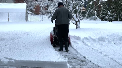 Man using a snow blower to clear the snow off his driveway Stock Footage 144684034