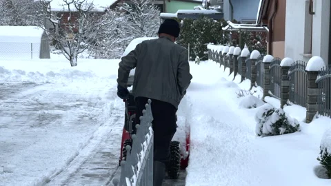 Man using a snow blower to clear the snow off his driveway Stock Footage 144684375