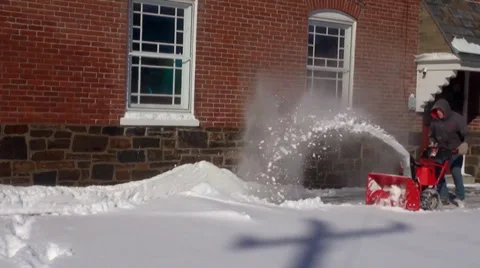 A man using a snow blower on a sidewalk Stock Footage 34356686