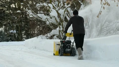 Man using snow plow machine to clear the driveway to the road in winter. Russia. Stock Footage 171557702