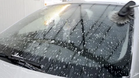 Man using a soap brush on a windshield at a self-service car wash station 스톡 동영상 141549299