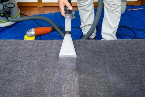 Man using a special vacuum to clean sofa cushions. Stock Photos