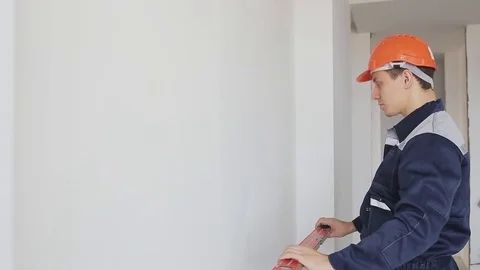Man using a spirit level to check wall indoor Stock Footage 76986141