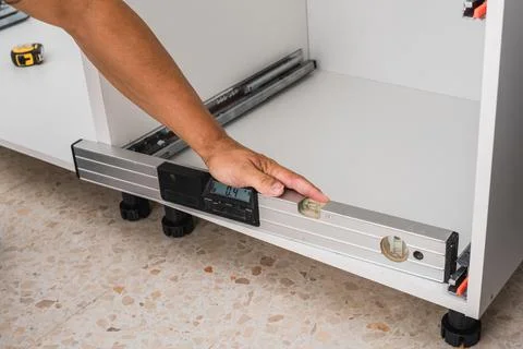 Man using a spirit level to check the installation of furniture Stock Photos