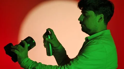 Man Using Spray on Camera Lens in Studio Vídeos de archivo 334108455