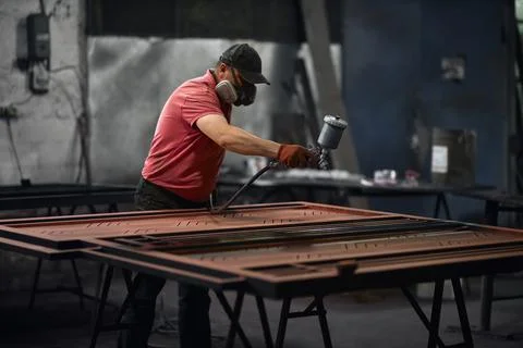 Man using spray compressor for painting metal details Stock Photos