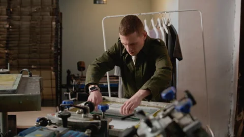 Man Using Squeegee on Screen Printing Frame in Workshop Stock-Footage 333160942