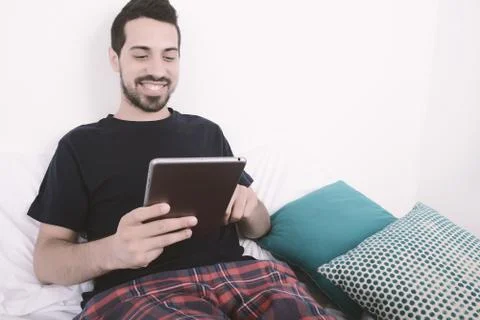 Man using tablet on bed. Stock-Fotos
