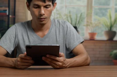 Man Using a Tablet in a Bright Modern Indoor Space with Plants Stock Photos