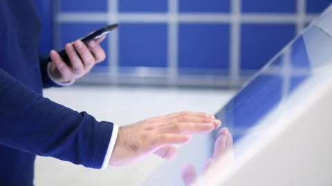 A man is using a tablet with a cell phone in his hand Stock Photos