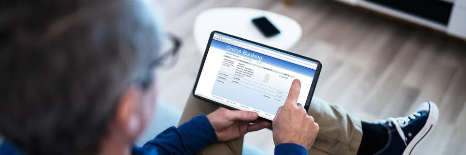 Man Using Tablet Computer Checking Bank Statement 写真素材
