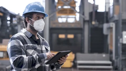 Man using a tablet computer in an industrial hall with a mask on Stock Footage 149294641