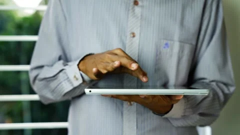 Man using tablet computer near window, Close-up of a man in a striped shirt.. Stock Footage 348346119