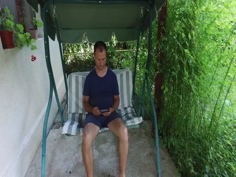 Man using tablet computer touchscreen while sitting on the swing and relax Video stock 79055963