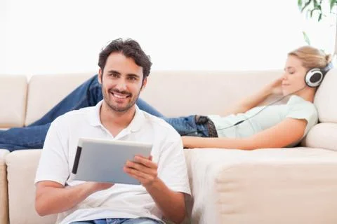 Man using a tablet computer while his wife is listening to music 스톡 사진