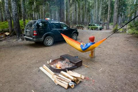 Man using tablet computer while relaxing in hammock by fire pit Stock Photos