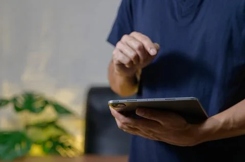 Man Using Tablet Device in Modern Indoor Setting with Greenery Foto stock