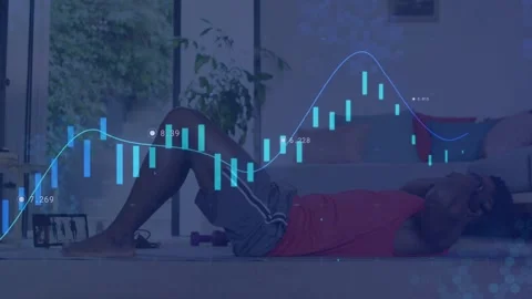Man using tablet doing sit-ups on mat to train core, finance charts overlaying Stock Footage 333397137