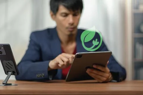 Man Using Tablet with Eco-Friendly Leaf Icon in Business Office Setting Stock Photos