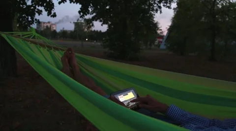 Man using a tablet in a hammock Stock Footage 54956173