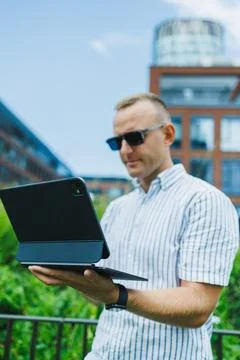 Man using a tablet outdoors in a city setting during daytime Stock Photos