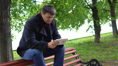 The man is using a tablet in the park. Video stock 91204104