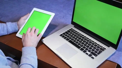 Man is using tablet pc and laptop. Laptop is lying on the table. Green screen Stock Footage 61280824