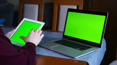 Man is using tablet pc and laptop. Laptop is lying on the table. Green screen Stock Footage 61281664