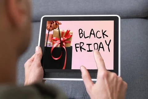 Man using tablet pc and selecting black friday. Stock Photos