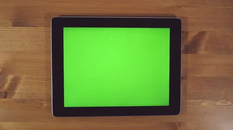 Man Using Tablet PC with Green Screen on a Wooden Background Stockbeeldmateriaal 61873140