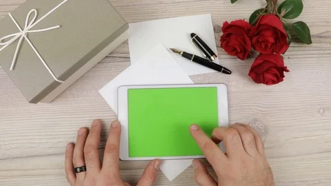 A man using a Tablet PC with green empty screen on a wooden table Stock Footage 85632508