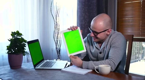 Man using tablet pc. He is showing the screen. Green screen. Stuff on the table. Stock Footage 61281410