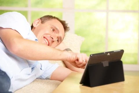 Man using tablet on sofa Stock Photos
